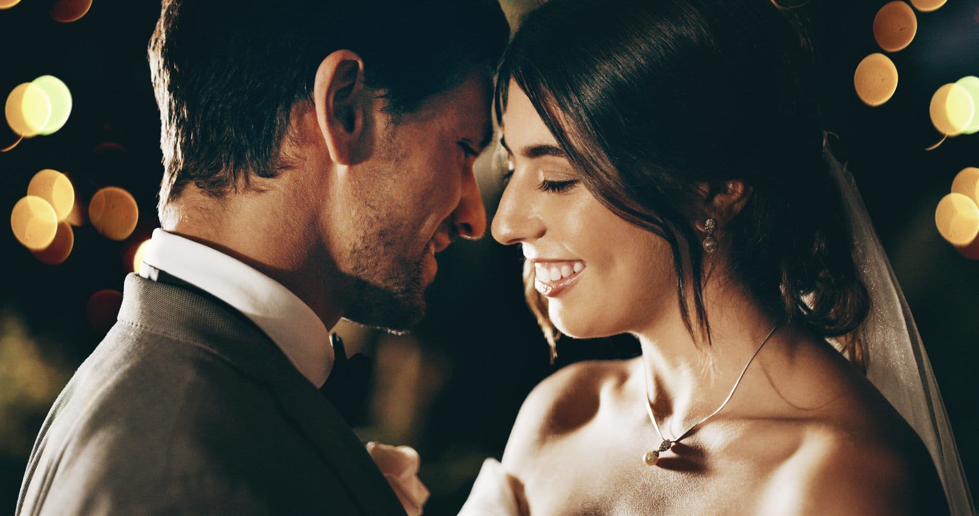 A couple resting their foreheads together, smiling, in warm evening light